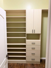 Light wood grain walk-in closet with black handles and rods. Adjustable shoe shelving. His and her closet