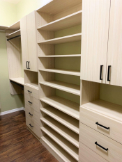 Light wood grain walk-in closet with black handles and rods. Adjustable shoe shelving. His and her closet