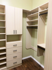 Light wood grain walk-in closet with black handles and rods. Adjustable shoe shelving. His and her closet