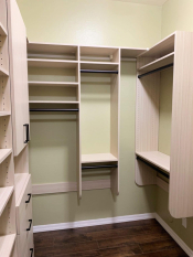 Light wood grain walk-in closet with black handles and rods. Adjustable shoe shelving. His and her closet
