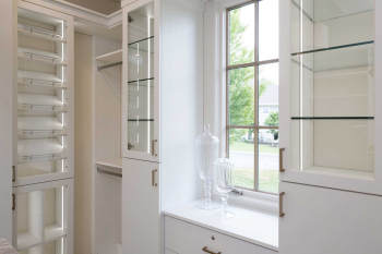 Luxury Walk-in Closet with Glass Display Case for Shoes and purses. Slab doors for other less elegant items. Walk-in Closet complete with island for jewelry.