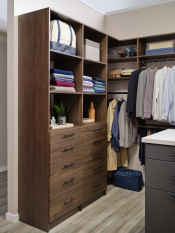 This designer walk-in closet boasts 2 tones a darker wood grain with a grey finish for the island to compliment the system and a stone countertop to complete this custom walk-in closet.