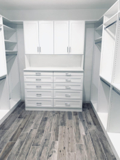 White walk-in closet system with drawers and doors. Lots of hanging and some shoe storage. Shaker drawer and door faces.