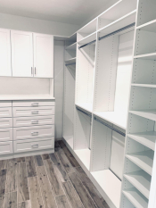 White walk-in closet system with drawers and doors. Lots of hanging and some shoe storage. Shaker drawer and door faces.