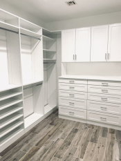 White walk-in closet system with drawers and doors. Lots of hanging and some shoe storage. Shaker drawer and door faces.