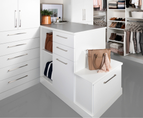 White walk-in closet with island built-into wall. A center display with his and her sides.