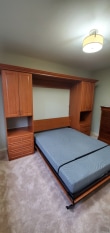 Wood grain murphy bed with shaker door and drawer faces. Crown molding trim.