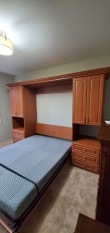 Wood grain murphy bed with shaker door and drawer faces. Crown molding trim.