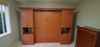 Wood grain murphy bed with shaker door and drawer faces. Crown molding trim.