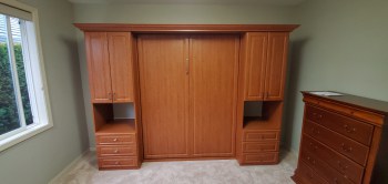 Wood grain murphy bed with shaker door and drawer faces. Crown molding trim.