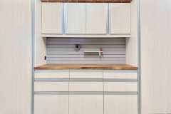 Bianco custom garage cabinets with a butcher block american walnut countertop. Extruded aluminum handles. Slat wall for tool storage and organization. Big side cabinets and lots of drawer storage.