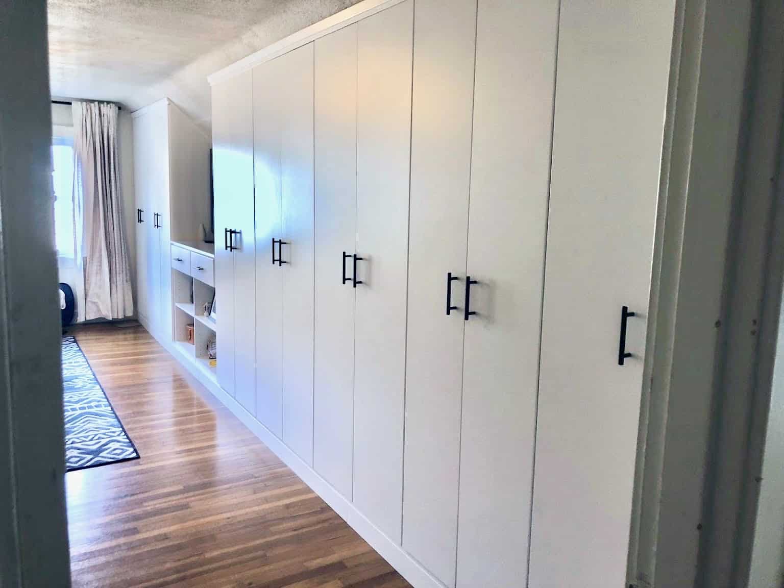 A custom built-in closet wardrobe otherwise known as an external closet or closet built-in. It includes a drawer bank, pull out trays, double hanging, roll out shelves, and upper storage.