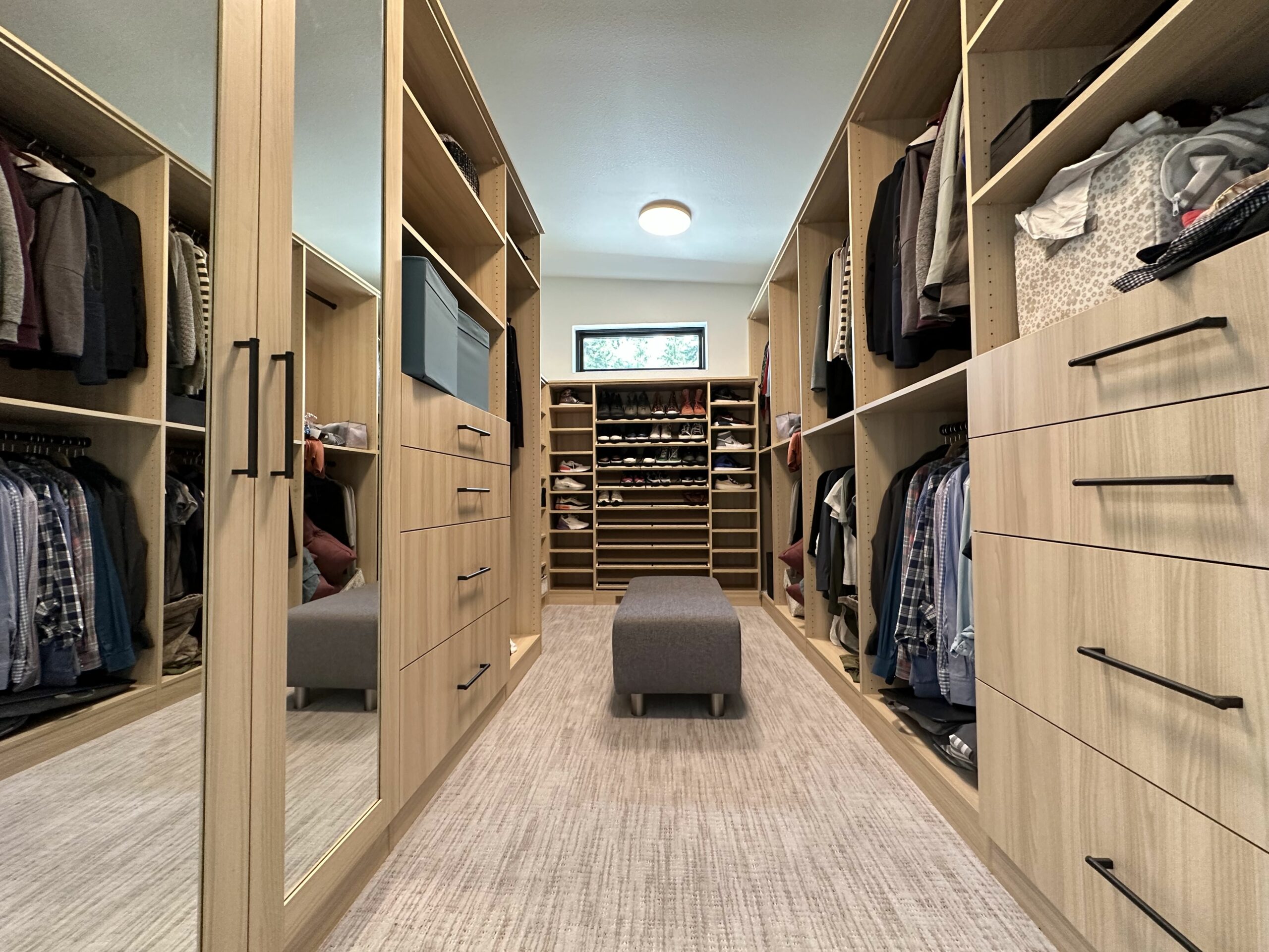 Light woodgrain walk-in closet with drawers, lots of shoe storage, drawers, jewelry inserts, tilt out hampers, and more.