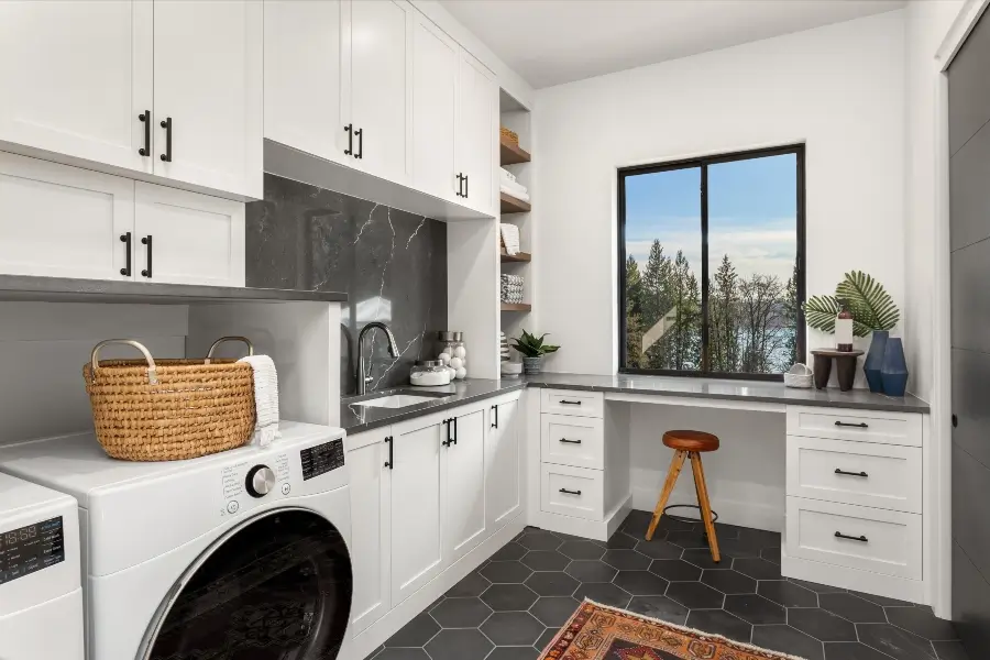 white and gray laundry room with custom cabinets, sink, desk, quartz counters, and backsplash