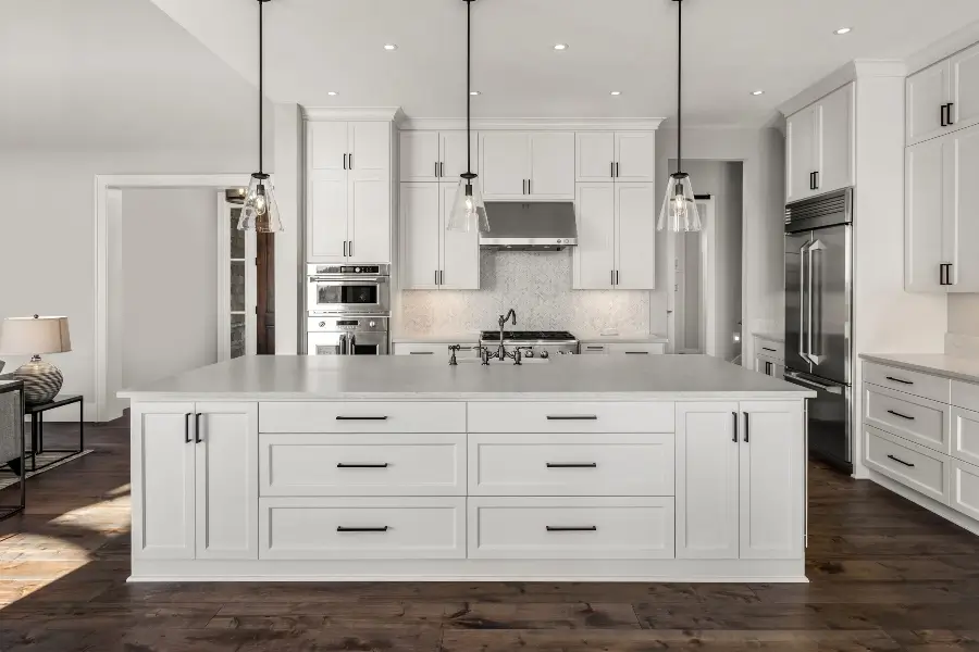 Custom kitchen island cabinets with stainless steel appliances, pendant lights, and hardwood floors