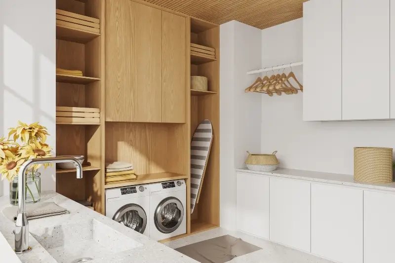 Interior of laundry room with custom storage, washing machine and dryer, iron board, sink, hangers, and decor