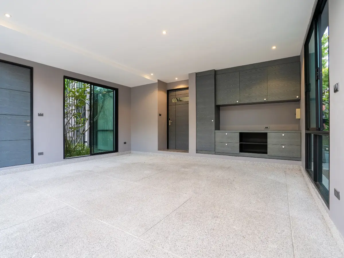 Wide-angle shot of a gray garage, with large windows, custom garage storage, and concrete flooring