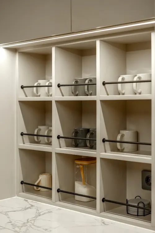 Built-in pantry shelves with neatly organized white and grey coffee mugs.