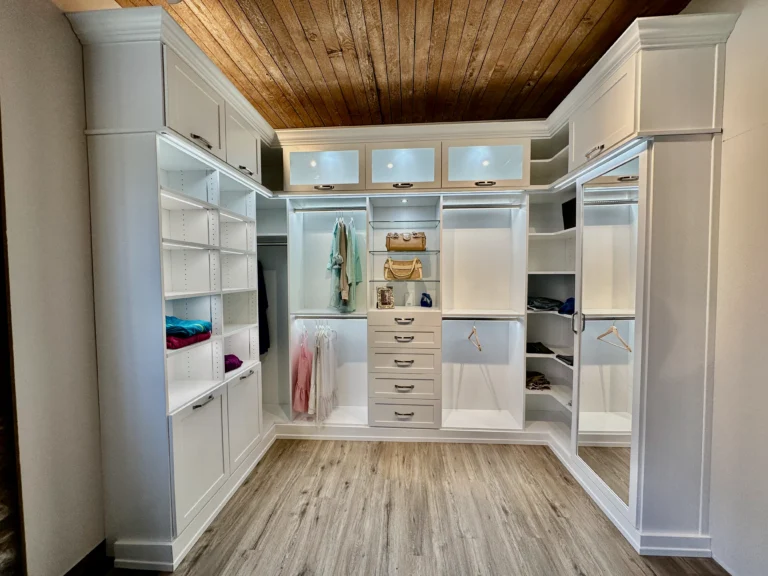 Custom walk-in closet features crisp white cabinetry finished with classic crown molding