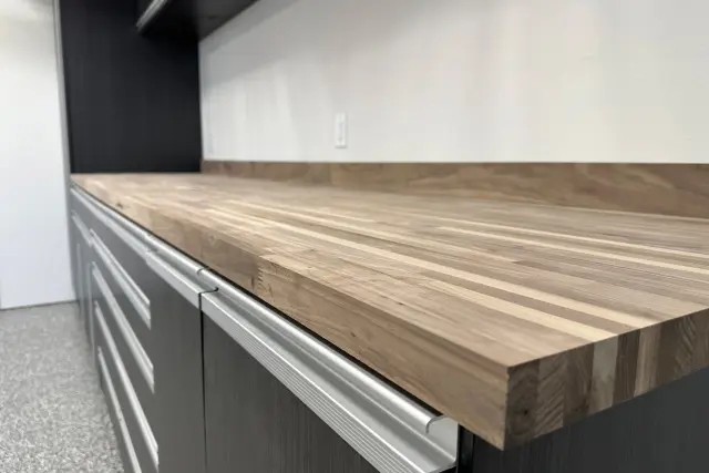 Close-up of a custom butcher block workbench countertop over dark cabinet drawers installed by Portland Closet Company in Portland, OR.