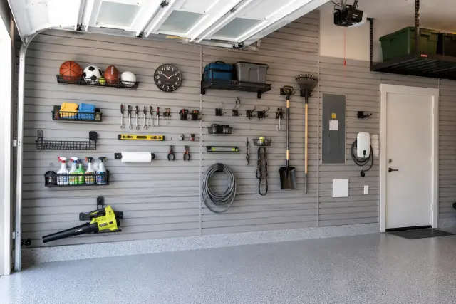 Full garage wall slatwall storage system featuring sports equipment racks and tool holders by Portland Closet Company.
